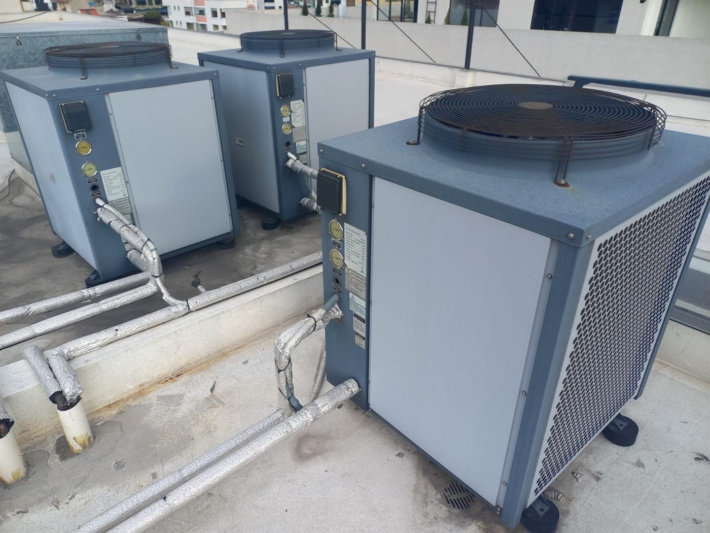 Tres bombas de calor aire-agua con tuberías hidráulicas aisladas instaladas en una terraza