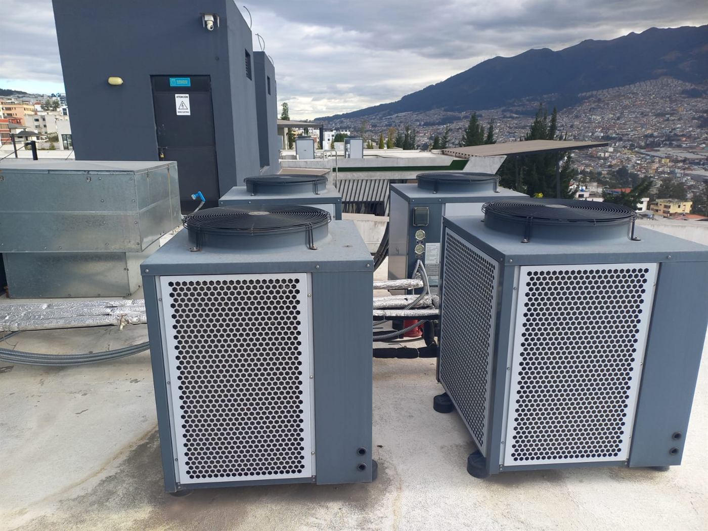 Cuatro bombas de calor aire-agua instaladas en la azotea de un edificio, con Quito y la montaña al fondo