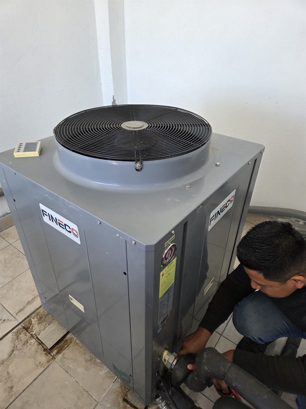 Técnico de ISIYER realizando mantenimiento en la conexión hidráulica de una bomba de calor FINEC