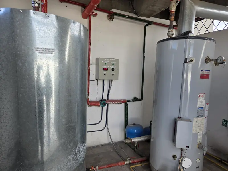Sala de agua caliente de un edificio con calentador a gas y tanque acumulador