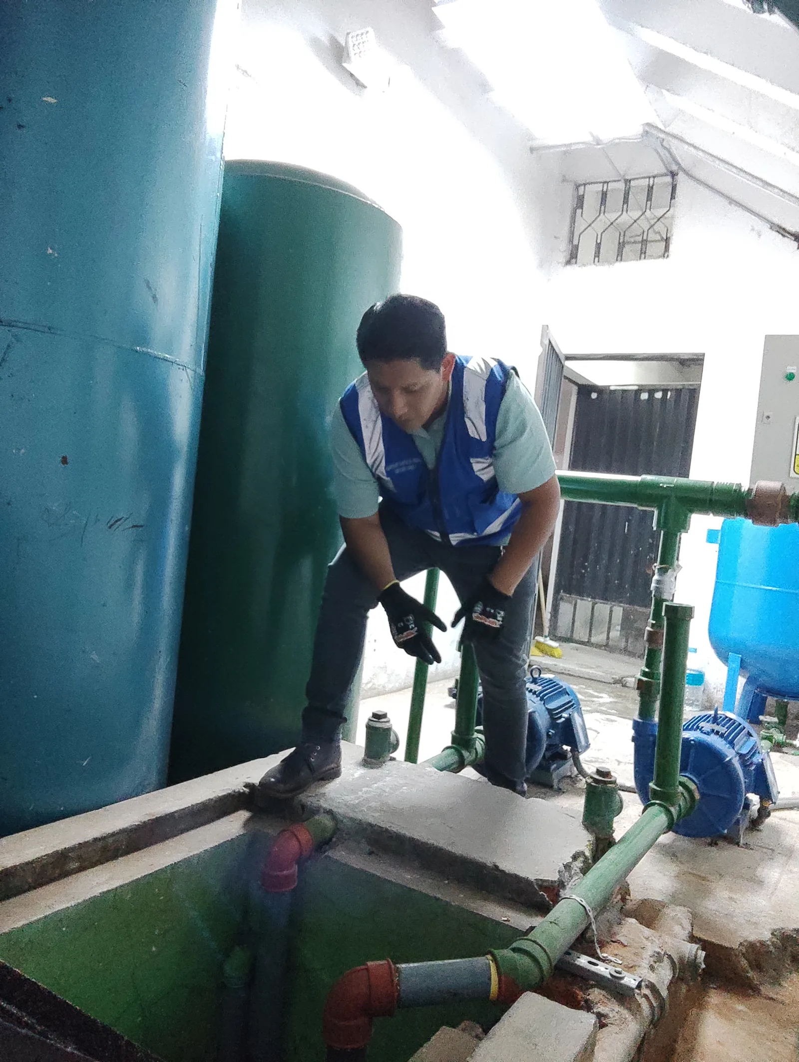 Técnico inspeccionando tuberías y bombas junto a una cisterna