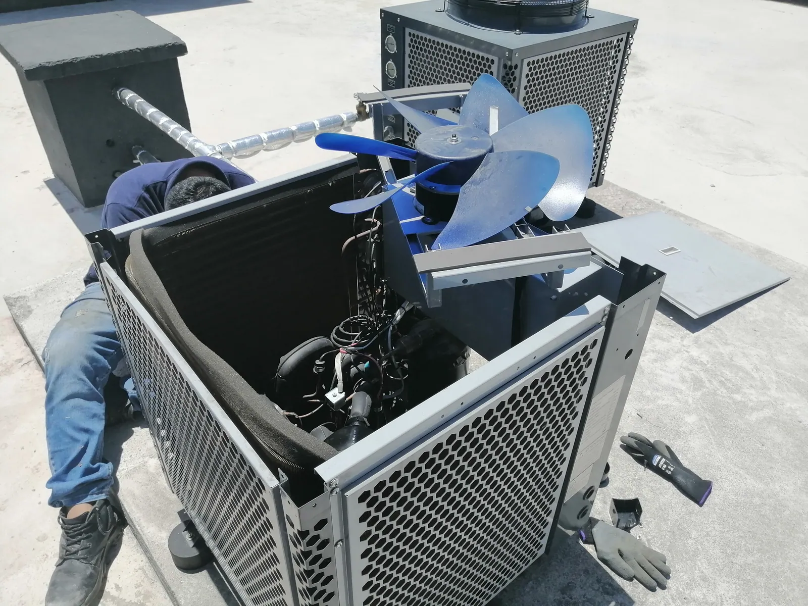 Técnico revisando una unidad exterior de aire acondicionado abierta durante una intervención