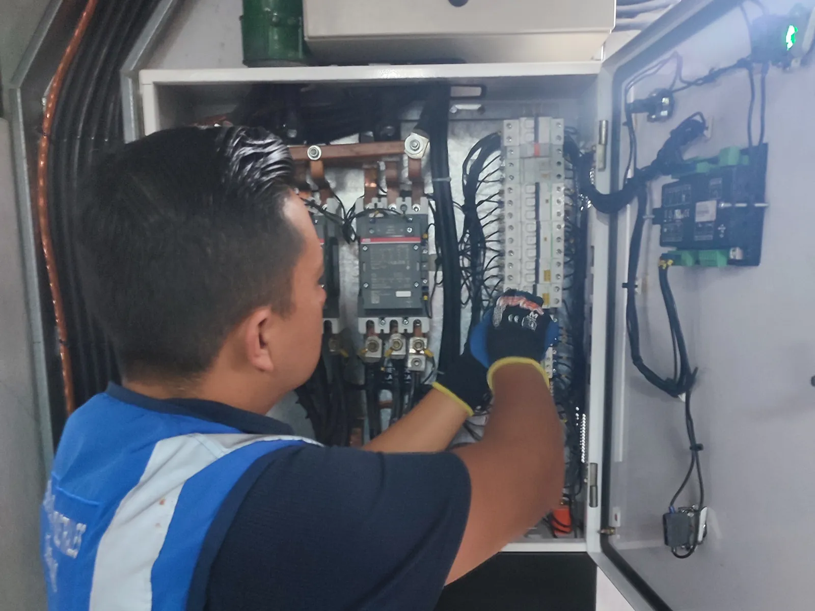 Técnico inspeccionando componentes dentro de un tablero eléctrico