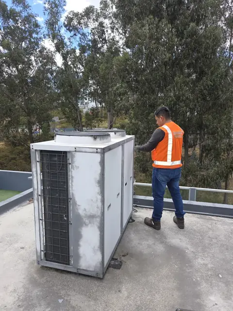 Técnico junto a bomba de calor en terraza de edificio en Quito