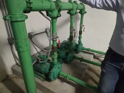 Sistema de bombeo con tuberías y válvulas en sala de máquinas de un edificio en Quito
